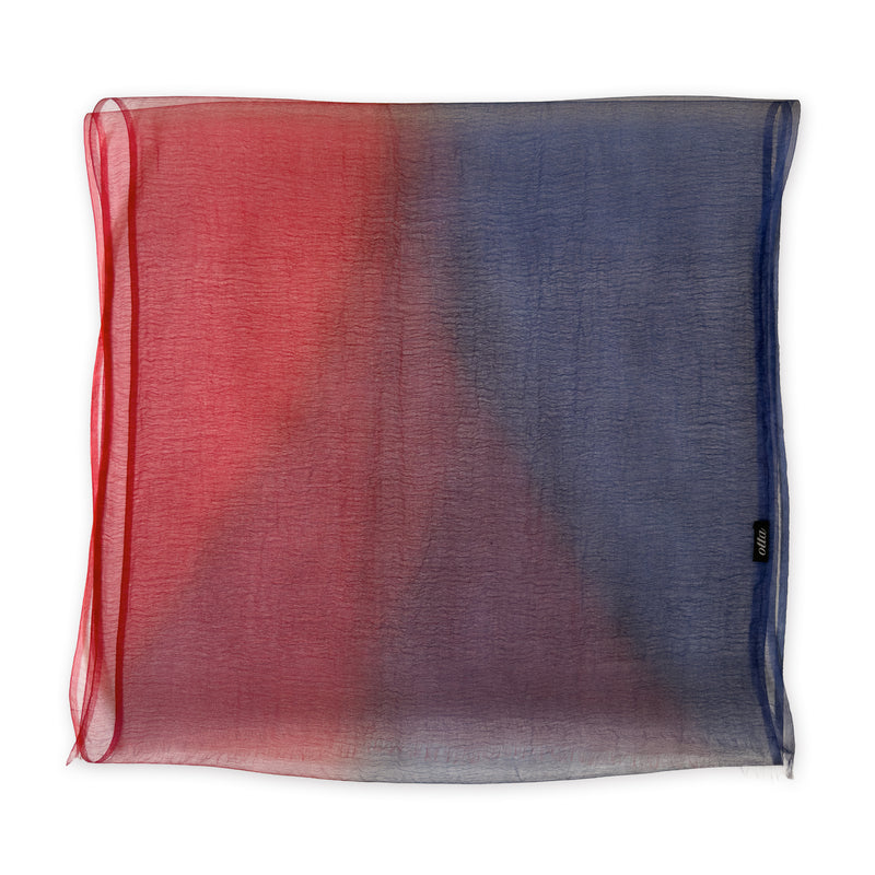 Colorful silk scarf in red and blue shades on a white background. t is hand-painted scarf in measures 48 x 194 cm by otta-italy scarves brand. Luxury Italian silk accessory, soft and lightweight scarf for women and men.