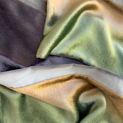 Close-up of a hand-painted Otta velvet scarf showcasing rich textures of green, beige and blue navy with detailed hand-sewn edges.
