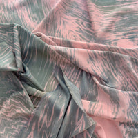 Close-up of a hand-painted Otta silk cotton blend scarf draped softly, showcasing gentle shades of 
pink and green. Lightweight artisan accessory with delicate hand-fringed edges, measuring 70 x 190 cm.

