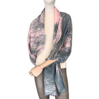 Mannequin wearing a hand-painted Otta silk cotton blend scarf on a white background in 
pink and green e tones. soft, fresh and lightweight, and elegant accessory measuring 70 x 190 cm. Unique artisan scarf with hand-fringed edges, perfect for women and men.
