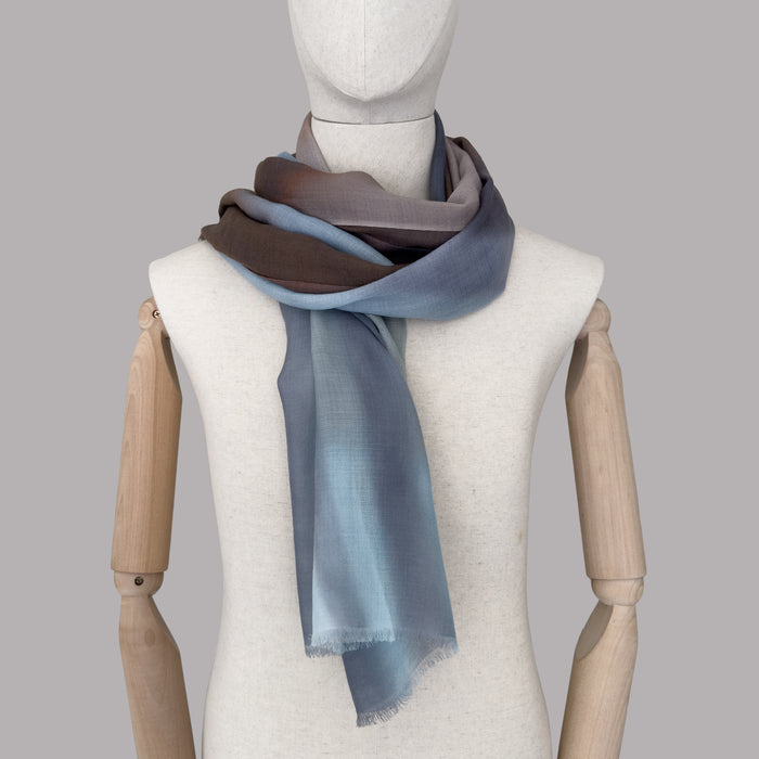 Mannequin wearing a hand-painted pure cashmere scarf by Otta-Italy, gray background. Light blue, beige, brown and gray shades. 67x195 cm.