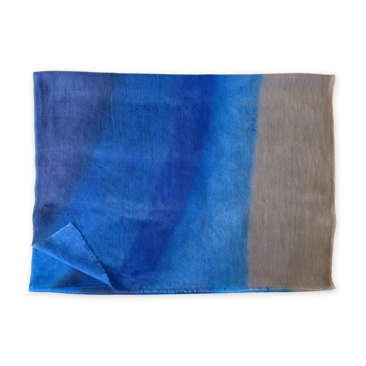 Folded fabric with blue and brown gradient on a white background. cashmere-scarf-hand-painted-69x207cm-indigo-sky-blue-midnight-blue-brown-otta-italy