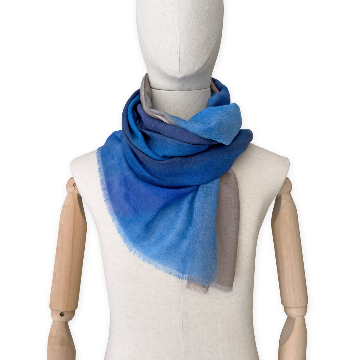 Mannequin wearing a blue scarf on a white background. cashmere-scarf-hand-painted-69x207cm-indigo-sky-blue-midnight-blue-brown-otta-italy