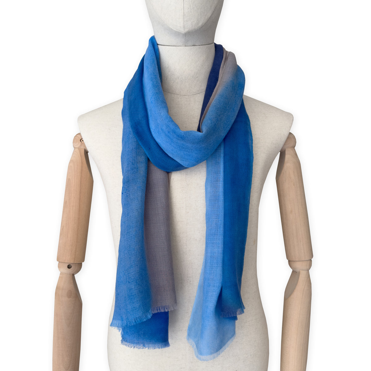 Mannequin wearing a blue scarf on a white background. cashmere-scarf-hand-painted-69x207cm-indigo-sky-blue-midnight-blue-brown-otta-italy