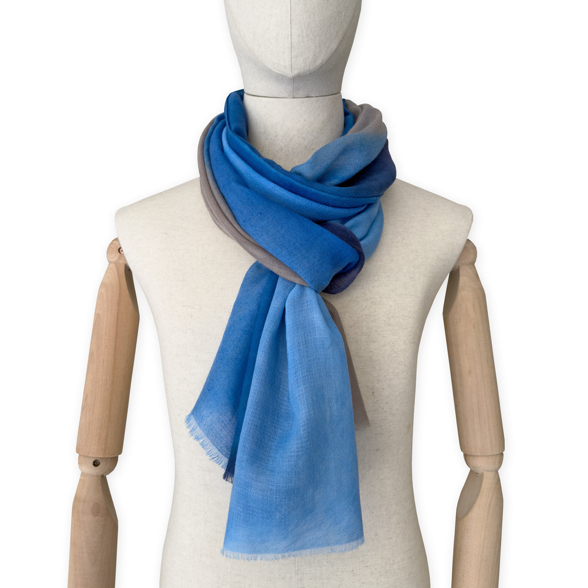 Mannequin wearing a blue scarf on a white background. cashmere-scarf-hand-painted-69x207cm-indigo-sky-blue-midnight-blue-brown-otta-italy
