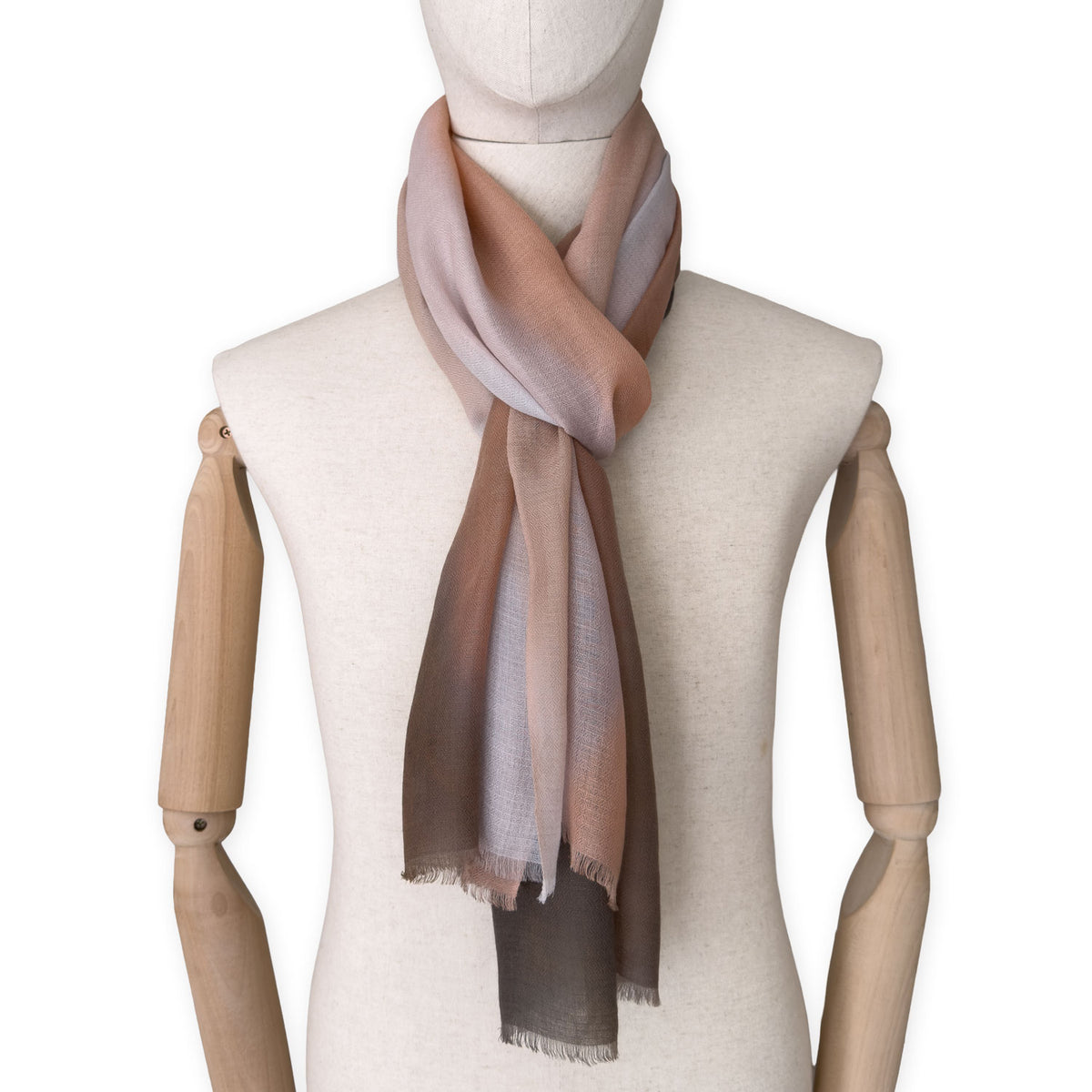 Mannequin wearing an elegant hand-painted Otta pure cashmere scarf on a white background. Warm brown, peach, beige and gray tones.
