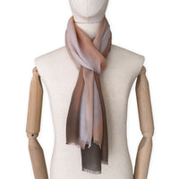 Mannequin wearing an elegant hand-painted Otta pure cashmere scarf on a white background. Warm brown, peach, beige and gray tones.
