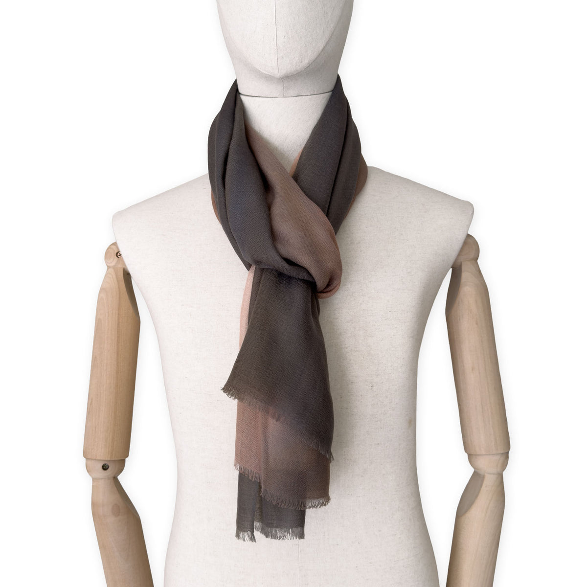 Mannequin wearing an elegant hand-painted Otta pure cashmere scarf on a white background. Warm brown, peach, beige and gray tones.
