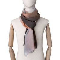 Mannequin wearing an elegant hand-painted Otta pure cashmere scarf on a white background. Warm brown, peach, beige and gray tones.
