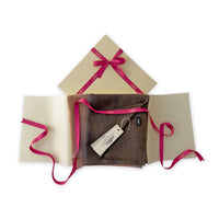 Luxury gift box with a pink ribbon containing a hand-painted Otta pure cashmere scarf on a white background.
