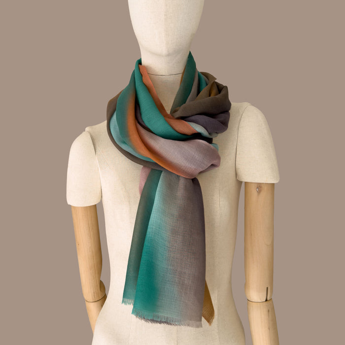Mannequin wearing a hand-painted pure cashmere scarf by Otta-Italy, beige background. brown, emerald green, coral and gray shades. 68x198 cm.
