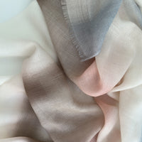 Close-up of soft fabric. Hand-painted pure cashmere scarf by Otta-Italy, 66 x 200 cm, featuring light gray, beige, pink and brown. Luxury Italian cashmere accessory, soft and warm scarf for women and men.
