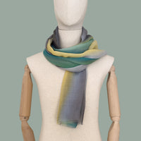 Mannequin wearing scarf on a gray background. Hand-painted cashmere scarf by Otta-Italy, 68 x 202 cm, featuring 
green, yellow, gray and brown. Luxury Italian pure cashmere accessory, soft and warm scarf for women and men.
