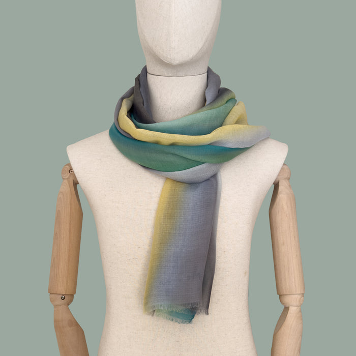 Mannequin wearing scarf on a gray background. Hand-painted cashmere scarf by Otta-Italy, 68 x 202 cm, featuring 
green, yellow, gray and brown. Luxury Italian pure cashmere accessory, soft and warm scarf for women and men.
