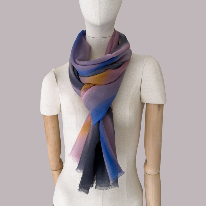 Mannequin wearing a hand-painted pure cashmere scarf by Otta-Italy, gray background. Pink, orange, blue and gray shades. 69 x 199 cm.
