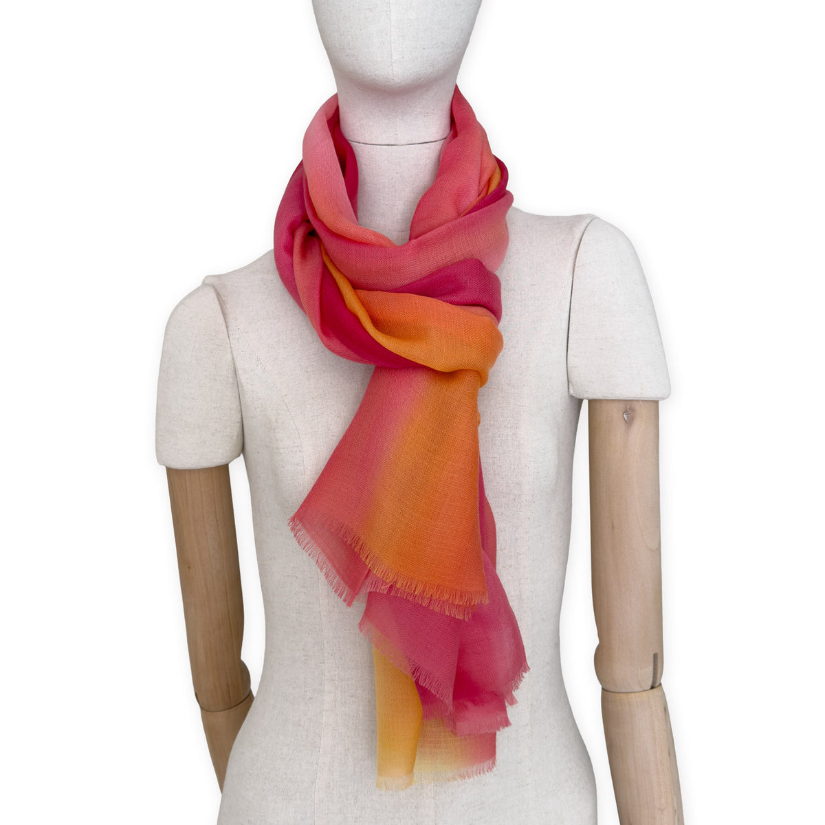Mannequin wearing an elegant hand-painted Otta pure cashmere scarf on a white background. Warm red, orange and yellow tones.

