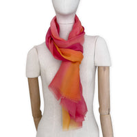 Mannequin wearing an elegant hand-painted Otta pure cashmere scarf on a white background. Warm red, orange and yellow tones.
