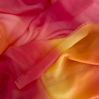 Close-up of hand-painted Otta pure cashmere scarf showcasing soft red, orange and yellow shades with delicate hand-fringed edges.
