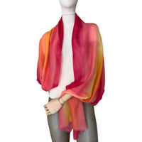 Mannequin wearing an elegant hand-painted Otta pure cashmere scarf on a white background. Warm red, orange and yellow tones.
