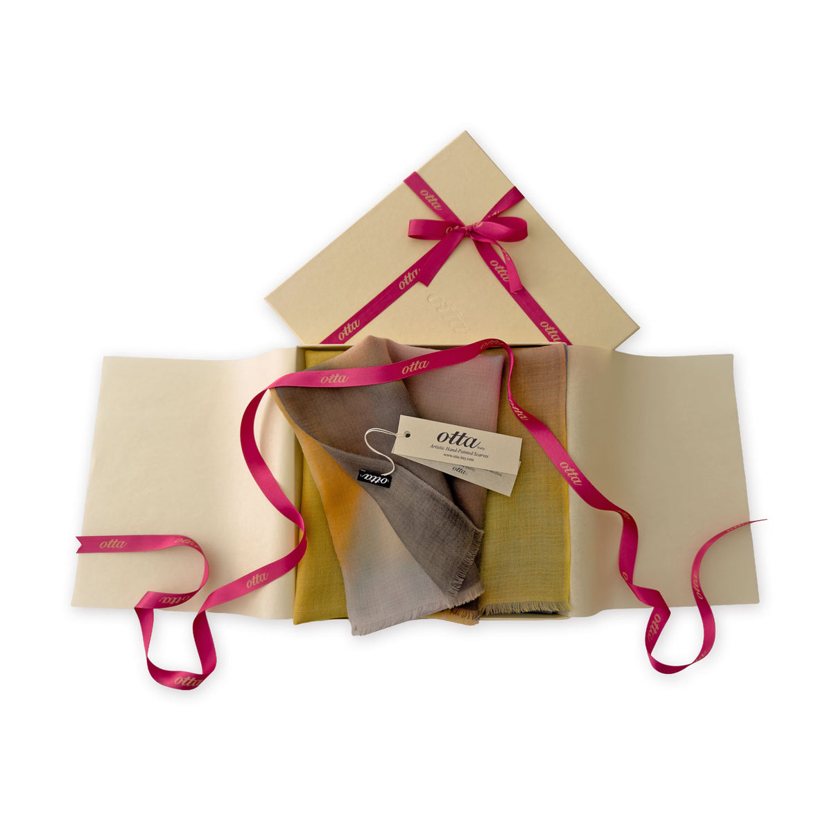 Luxury gift box with a pink ribbon containing a hand-painted Otta pure cashmere scarf on a white background.
