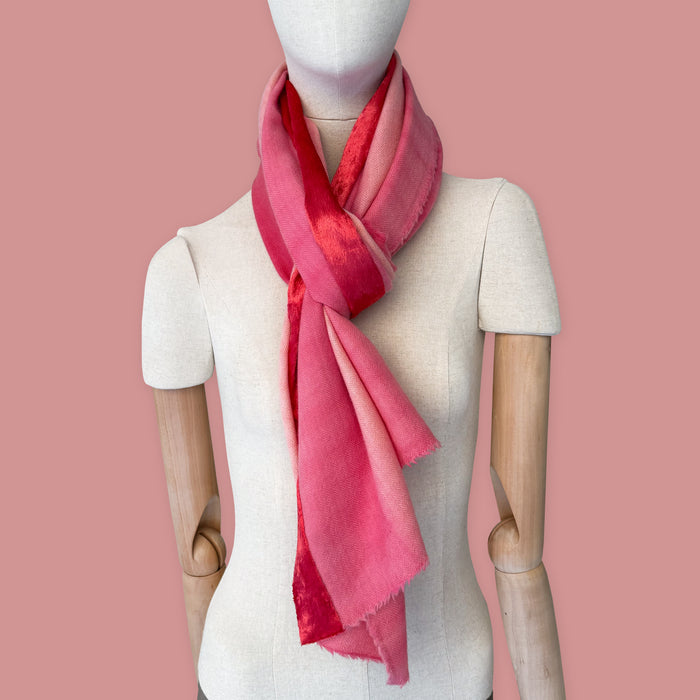Mannequin wearing scarf on a pink background. Hand-painted cashmere & wool scarf by Otta-Italy, 57 x 180 cm, featuring 
red, fuchsia and pink. Luxury Italian cashmere & wool accessory, soft and warm scarf for women and men.

