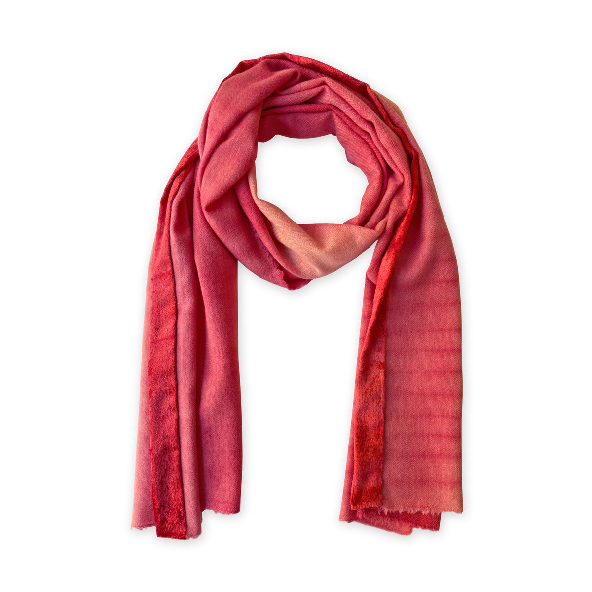 Hand-painted Otta cashmere & wool scarf in 
red, fuchsia and pink, loosely looped to showcase its full length and delicate texture in white background. Lightweight artisan accessory with hand-fringed edges, measuring 57 x 180 cm.

