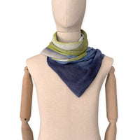 Mannequin wearing a hand-painted Otta pure linen scarf on a white background in 
blue, midnight blue, indigo, light blue, green tones. soft, fresh and lightweight, and elegant accessory measuring 34 x 192 cm. Unique artisan scarf with hand-sewn edges, perfect for women and men.
