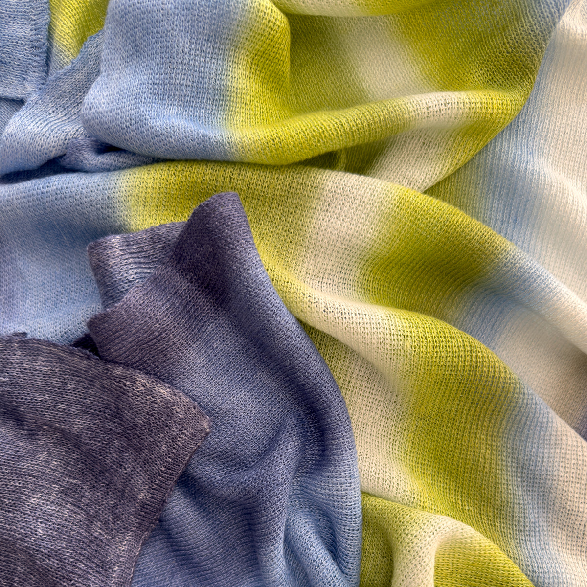 Mannequin wearing scarf on a pastel blue background. Hand-painted linen scarf by Otta-Italy, 34 x 192 cm, featuring 
blue, midnight blue, indigo, light blue, green. Luxury Italian pure linen accessory, soft, fresh and lightweight scarf for women and men.
