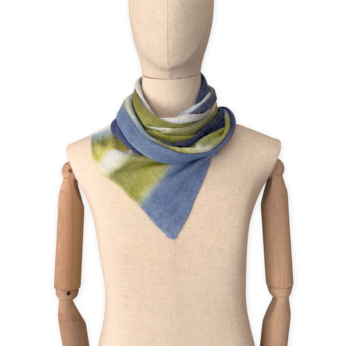 Mannequin wearing a hand-painted Otta pure linen scarf on a white background in 
blue, midnight blue, indigo, light blue, green tones. soft, fresh and lightweight, and elegant accessory measuring 34 x 192 cm. Unique artisan scarf with hand-sewn edges, perfect for women and men.
