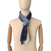 Mannequin wearing a hand-painted Otta pure linen scarf on a white background in 
blue, midnight blue, indigo, light blue, green tones. soft, fresh and lightweight, and elegant accessory measuring 34 x 192 cm. Unique artisan scarf with hand-sewn edges, perfect for women and men.
