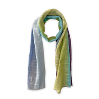 Hand-painted Otta pure linen scarf in 
blue, turquoise, green and purple, loosely looped to showcase its full length and delicate texture in white background. Lightweight artisan accessory with hand-sewn edges, measuring 70 x 190 cm.
