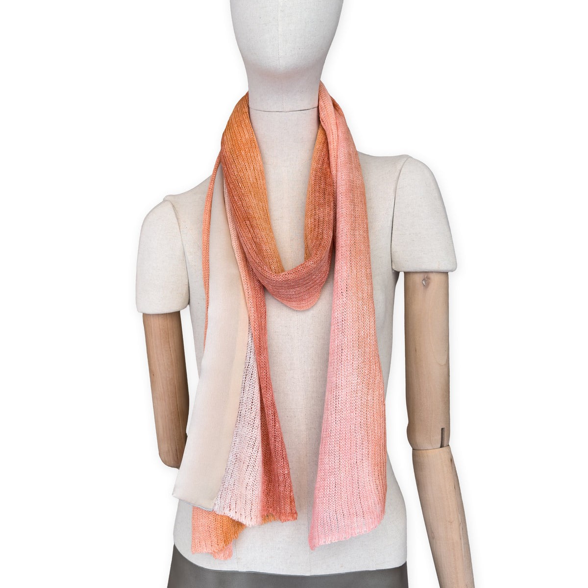 Mannequin wearing a hand-painted Otta pure linen scarf on a white background in 
coral, orange, gray, and champagne tones. soft, fresh and lightweight, and elegant accessory measuring 37 x 196 cm. Unique artisan scarf with hand-sewn edges, perfect for women and men.

