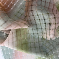 Close-up of soft fabric, a hand-painted Otta pure linen scarf draped softly, showcasing gentle shades of 
green and beigen. Lightweight artisan accessory with delicate hand-sewn edges, measuring 48 x 190 cm.
