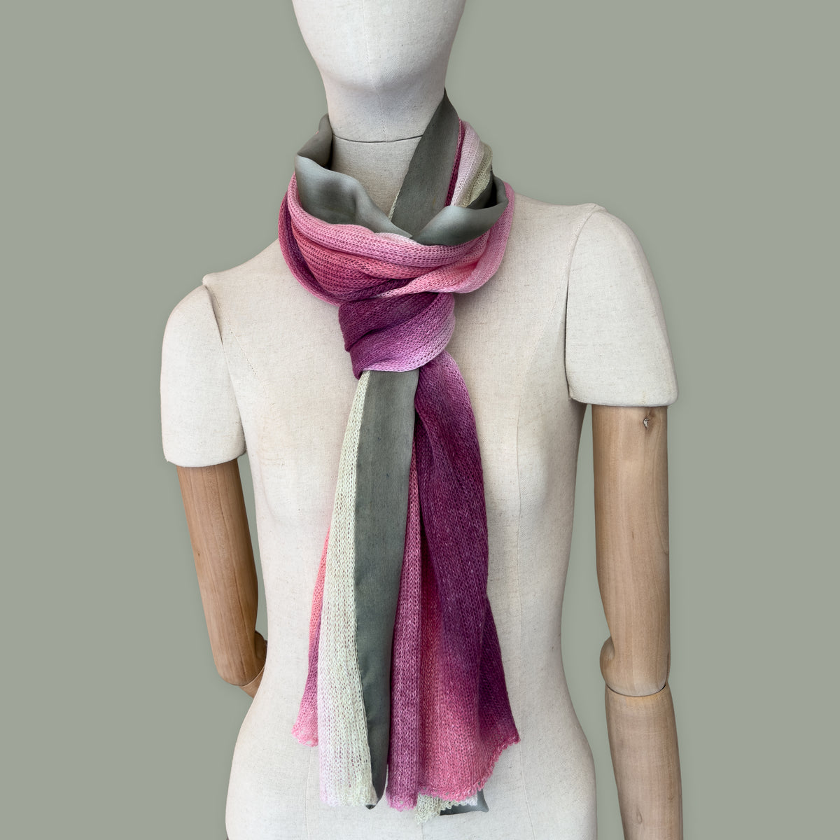 Mannequin wearing scarf on a gray background. Hand-painted linen scarf by Otta-Italy, 42 x 196 cm, featuring 
pink and green. Luxury Italian pure linen accessory, soft, fresh and lightweight scarf for women and men.
