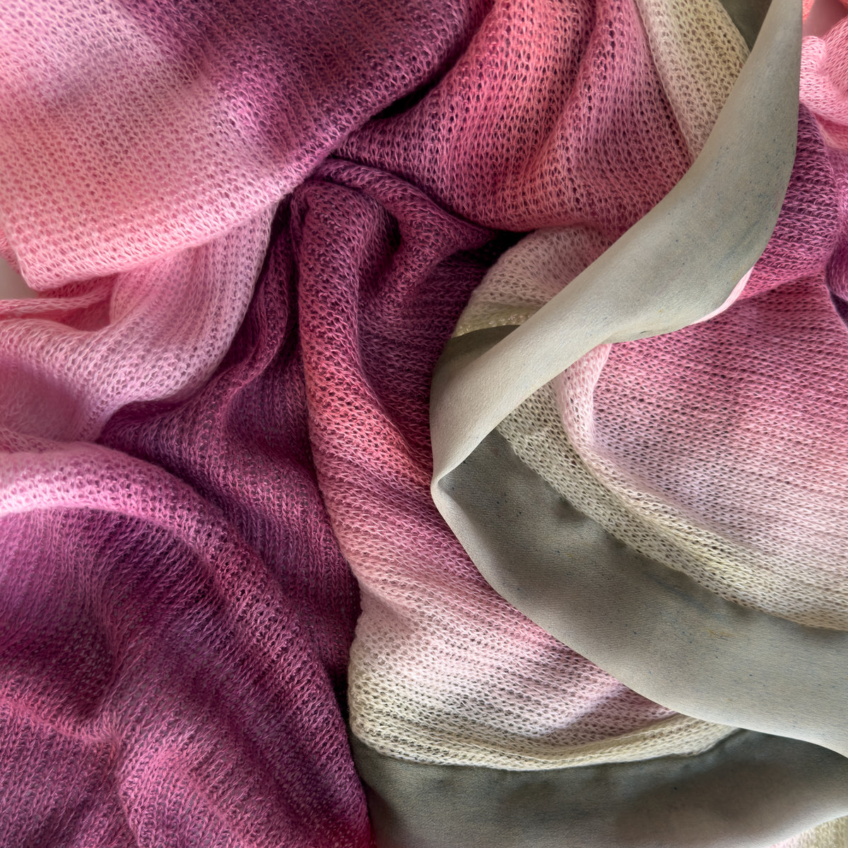 Close-up of a hand-painted Otta pure linen scarf draped softly, showcasing gentle shades of 
pink and green. Lightweight artisan accessory with delicate hand-sewn edges, measuring 42 x 196 cm.

