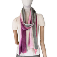 Mannequin wearing a hand-painted Otta pure linen scarf on a white background in 
pink and green tones. soft, fresh and lightweight, and elegant accessory measuring 42 x 196 cm. Unique artisan scarf with hand-sewn edges, perfect for women and men.

