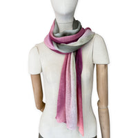Mannequin wearing a hand-painted Otta pure linen scarf on a white background in 
pink and green tones. soft, fresh and lightweight, and elegant accessory measuring 42 x 196 cm. Unique artisan scarf with hand-sewn edges, perfect for women and men.
