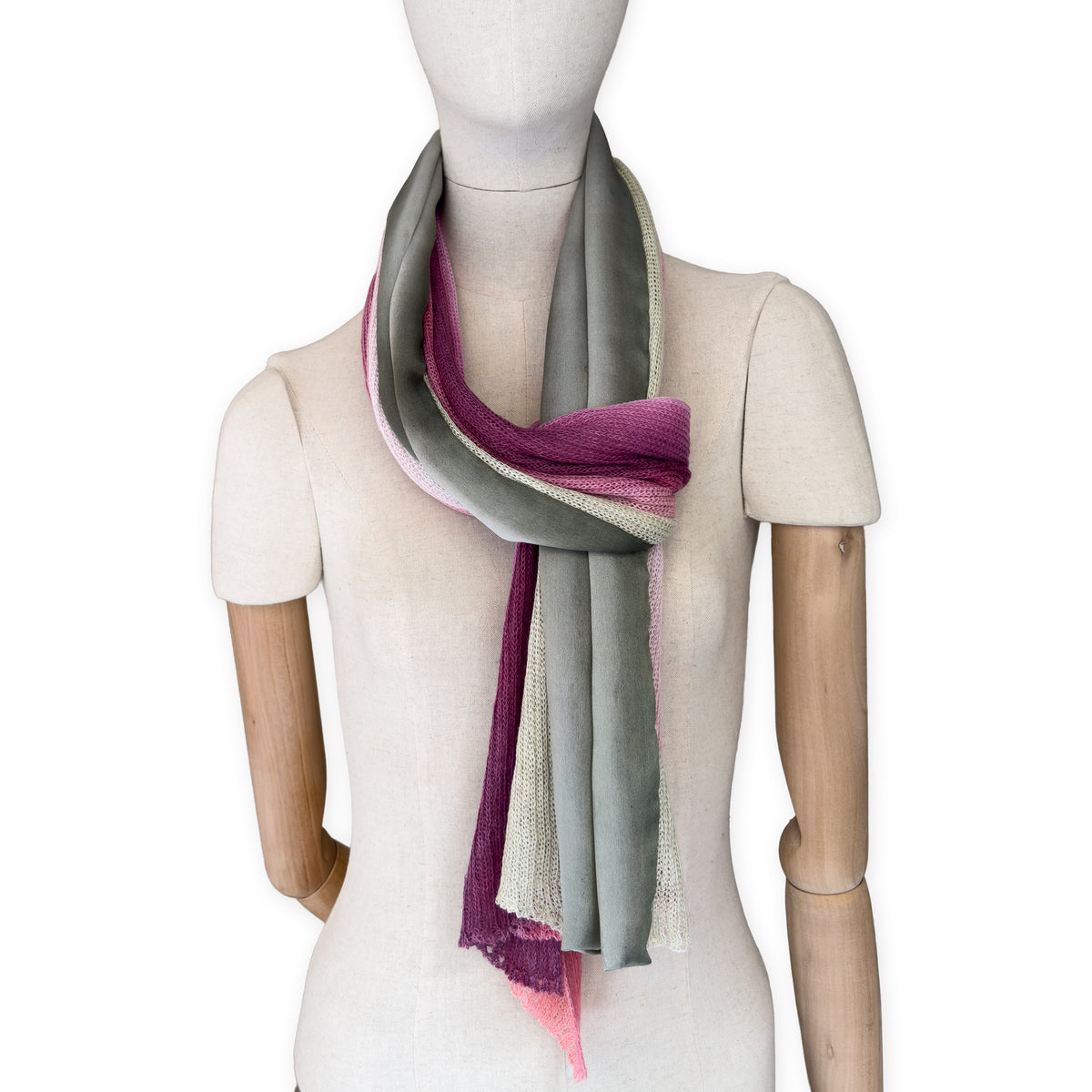 Mannequin wearing a hand-painted Otta pure linen scarf on a white background in 
pink and green tones. soft, fresh and lightweight, and elegant accessory measuring 42 x 196 cm. Unique artisan scarf with hand-sewn edges, perfect for women and men.
