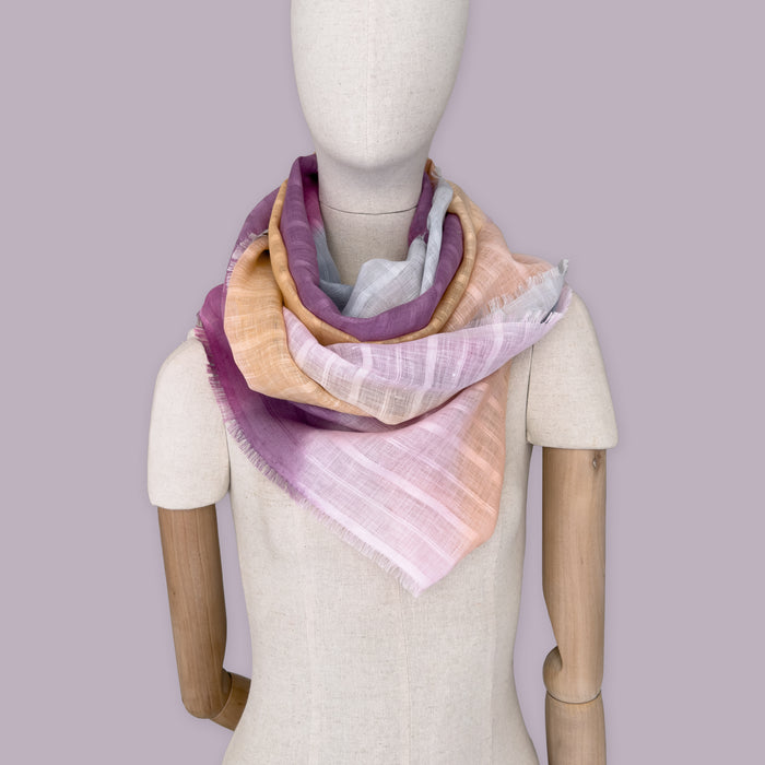 Mannequin wearing scarf on a pastel green background. Hand-painted linen scarf by Otta-Italy, 70 x 190 cm, featuring 
pink, peach, fuchsia and gray. Luxury Italian pure linen accessory, soft, fresh and lightweight scarf for women and men.
