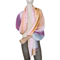 Mannequin wearing a hand-painted Otta pure linen scarf on a white background in 
pink, peach, fuchsia and gray tones. soft, fresh and lightweight, and elegant accessory measuring 70 x 190 cm. Unique artisan scarf with hand-sewn edges, perfect for women and men.
