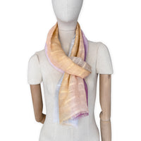 Mannequin wearing a hand-painted Otta pure linen scarf on a white background in 
pink, peach, fuchsia and gray tones. soft, fresh and lightweight, and elegant accessory measuring 70 x 190 cm. Unique artisan scarf with hand-sewn edges, perfect for women and men.
