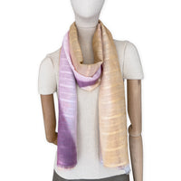 Mannequin wearing a hand-painted Otta pure linen scarf on a white background in 
pink, peach, fuchsia and gray tones. soft, fresh and lightweight, and elegant accessory measuring 70 x 190 cm. Unique artisan scarf with hand-sewn edges, perfect for women and men.
