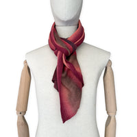Mannequin wearing a colorful and lightweight linen scarf on a white background. Linen scarf is in shades of red, coral and brown colors. It is hand-painted scarf in measures 32 x 200 cm by otta-italy scarves brand. Luxury Italian linen, soft and lightweight scarf for women and men.
