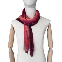 Mannequin wearing a colorful and lightweight linen scarf on a white background. Linen scarf is in shades of red, coral and brown colors. It is hand-painted scarf in measures 32 x 200 cm by otta-italy scarves brand. Luxury Italian linen, soft and lightweight scarf for women and men.
