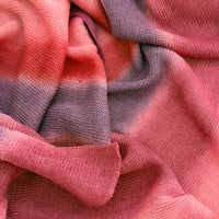 Close-up of soft fabric, a hand-painted Otta pure linen scarf draped softly, showcasing gentle shades of 
red and purple. Lightweight artisan accessory with delicate hand-sewn edges, measuring 33 x 205 cm.
