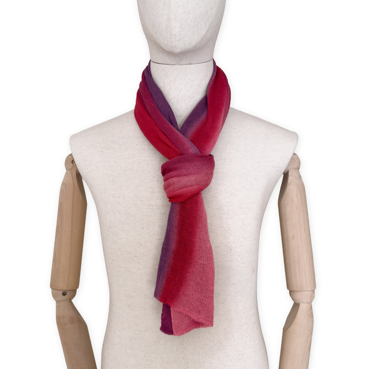 Mannequin wearing a hand-painted Otta pure linen scarf on a white background in 
red and purple tones. soft, fresh and lightweight, and elegant accessory measuring 33 x 205 cm. Unique artisan scarf with hand-sewn edges, perfect for women and men.

