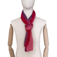 Mannequin wearing a hand-painted Otta pure linen scarf on a white background in 
red and purple tones. soft, fresh and lightweight, and elegant accessory measuring 33 x 205 cm. Unique artisan scarf with hand-sewn edges, perfect for women and men.
