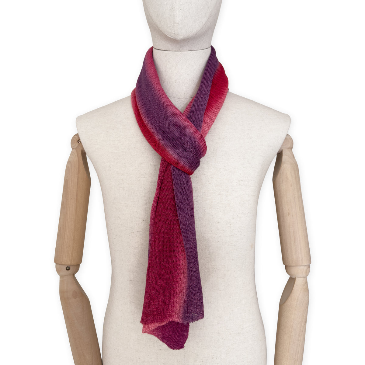Mannequin wearing a hand-painted Otta pure linen scarf on a white background in 
red and purple tones. soft, fresh and lightweight, and elegant accessory measuring 33 x 205 cm. Unique artisan scarf with hand-sewn edges, perfect for women and men.
