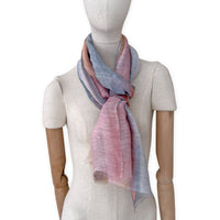 Mannequin wearing a hand-painted Otta pure linen scarf on a white background in 
coral, gray, brown, pink and blue tones. soft, fresh and lightweight, and elegant accessory measuring 52 x 200 cm. Unique artisan scarf with hand-sewn edges, perfect for women and men.

