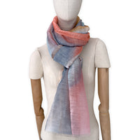 Mannequin wearing a hand-painted Otta pure linen scarf on a white background in 
coral, gray, brown, pink and blue tones. soft, fresh and lightweight, and elegant accessory measuring 52 x 200 cm. Unique artisan scarf with hand-sewn edges, perfect for women and men.
